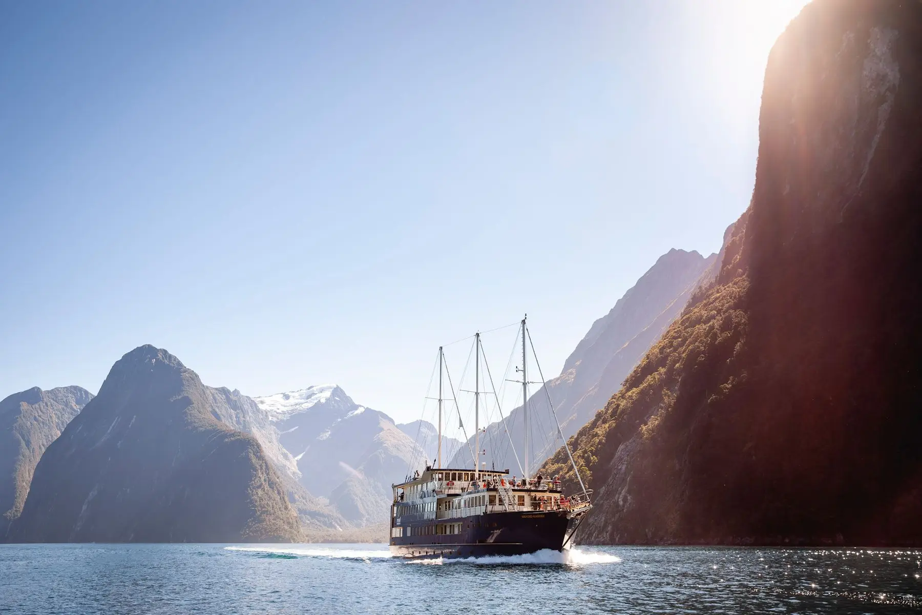 Image shows a fjord tour boat on Milford Sound, New Zealand