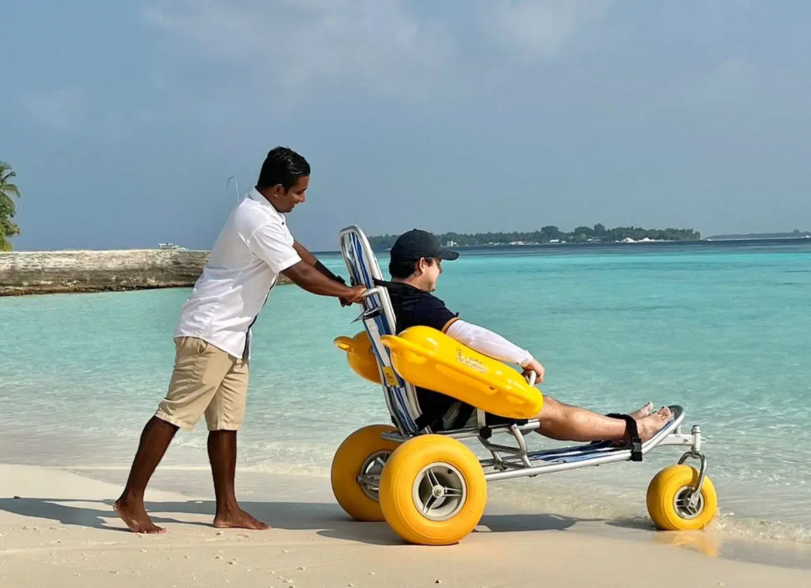 Image shows a guest using a floating wheelchair at Amilla Maldives