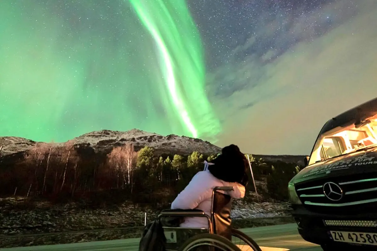 Image shows a female wheelchair user enjoying the Northern Lights in Norway